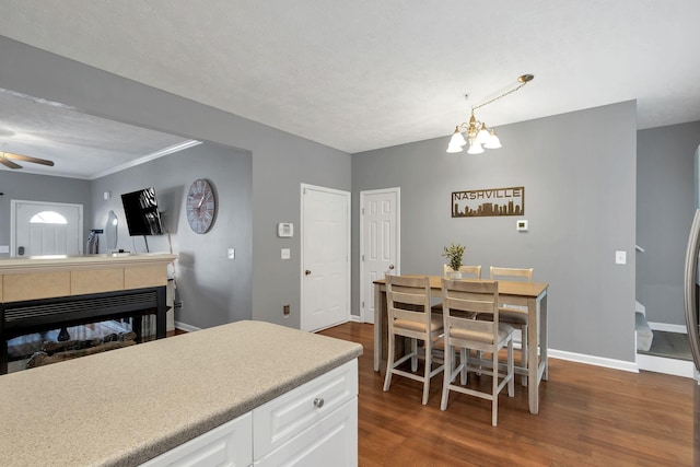 kitchen featuring decorative light fixtures, ceiling fan with notable chandelier, dark wood-type flooring, and white cabinetry