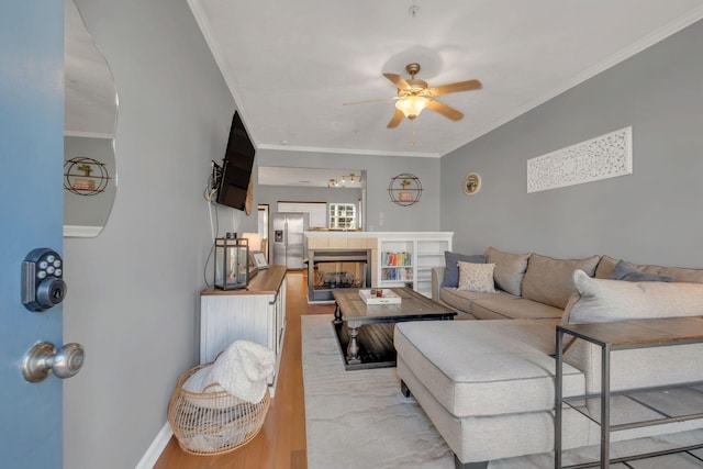 living room featuring crown molding, light hardwood / wood-style floors, a fireplace, and ceiling fan