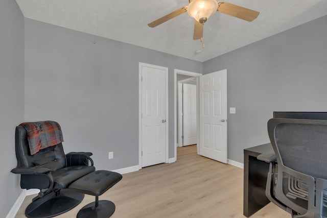 living area with light wood-type flooring, a textured ceiling, and ceiling fan