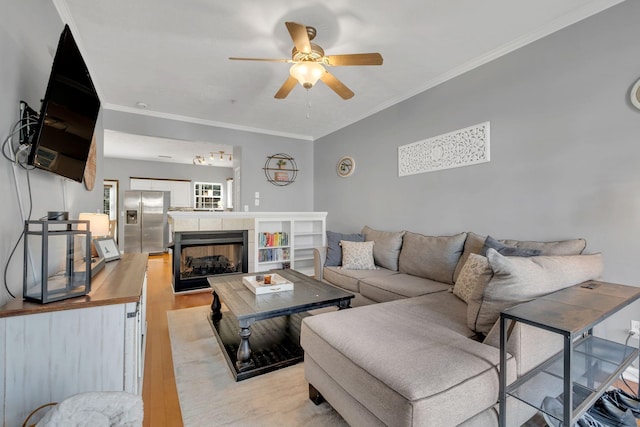 living room with light wood-type flooring, ceiling fan, and ornamental molding