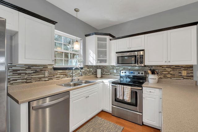 kitchen featuring sink, stainless steel appliances, white cabinets, and decorative light fixtures