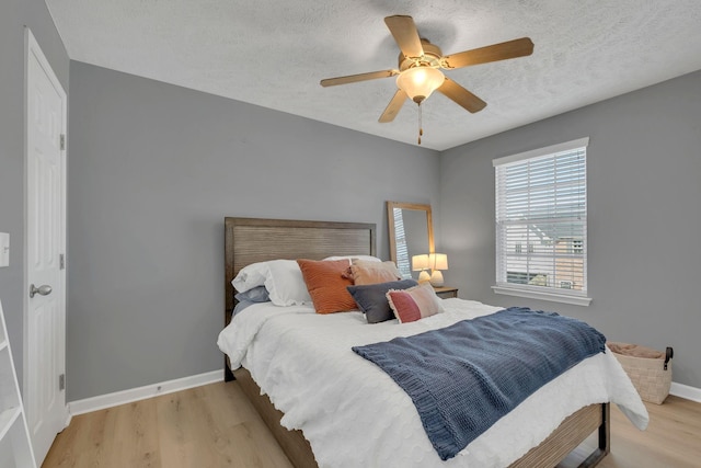 bedroom with ceiling fan, light hardwood / wood-style flooring, and a textured ceiling