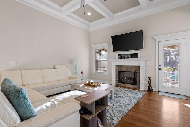 living room featuring wood-type flooring, a stone fireplace, beamed ceiling, crown molding, and coffered ceiling