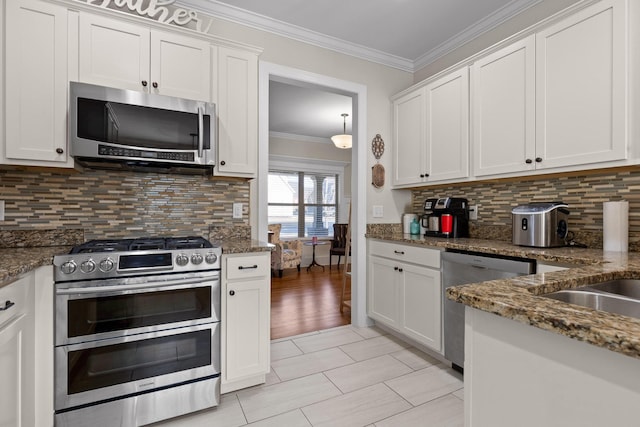 kitchen featuring appliances with stainless steel finishes, white cabinetry, dark stone counters, backsplash, and light tile patterned flooring