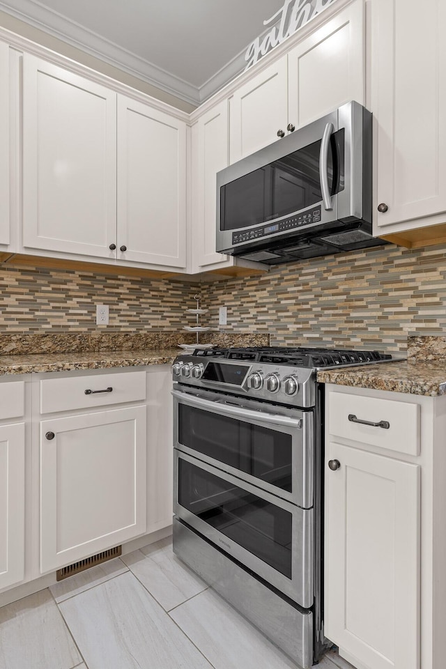 kitchen with backsplash, white cabinetry, and appliances with stainless steel finishes