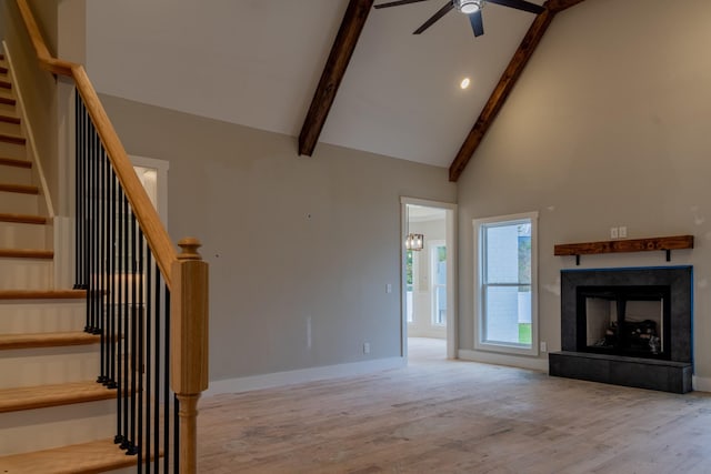 unfurnished living room featuring light hardwood / wood-style flooring, beamed ceiling, high vaulted ceiling, and ceiling fan