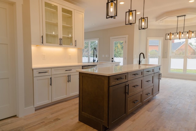 kitchen featuring decorative light fixtures, sink, white cabinetry, and light hardwood / wood-style flooring