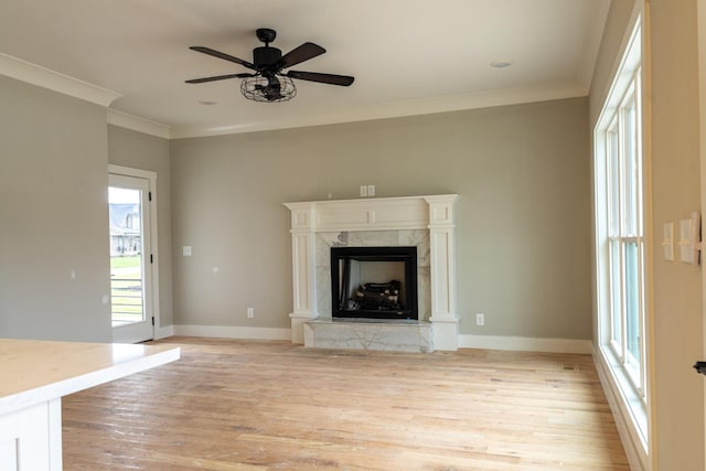 unfurnished living room featuring crown molding, light hardwood / wood-style floors, ceiling fan, and a premium fireplace