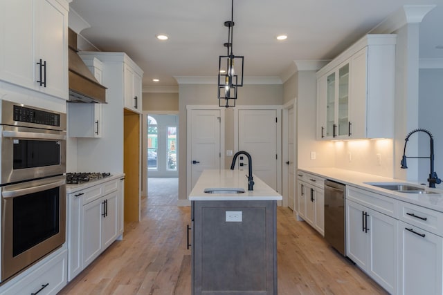 kitchen with sink, white cabinetry, appliances with stainless steel finishes, and an island with sink