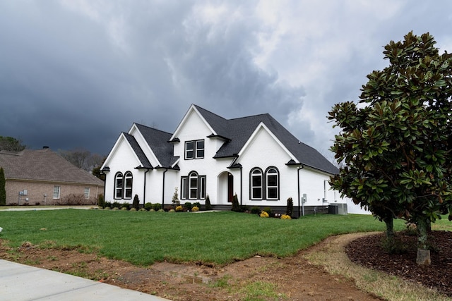 french provincial home with a front yard and central AC unit