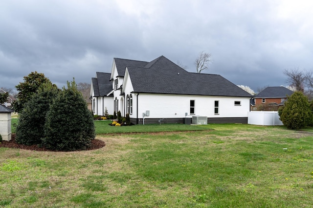 back of house with central air condition unit and a yard