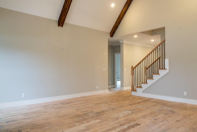 unfurnished living room with light wood-type flooring, beam ceiling, and high vaulted ceiling