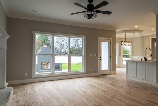 unfurnished living room with sink, light hardwood / wood-style floors, and crown molding