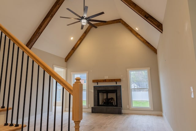 unfurnished living room featuring high vaulted ceiling, beam ceiling, and ceiling fan