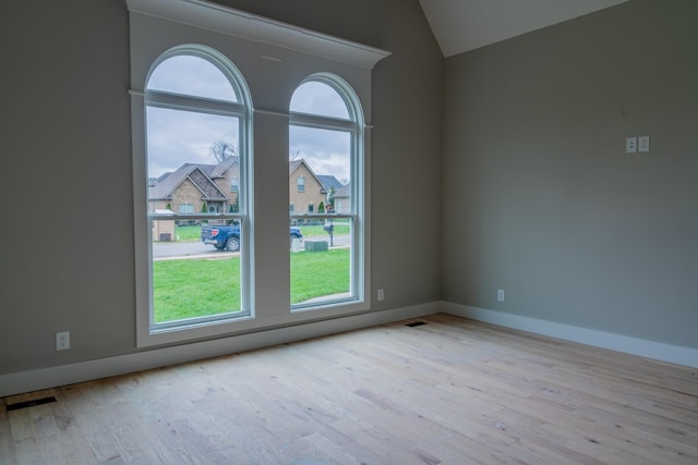 empty room featuring light wood-type flooring and vaulted ceiling