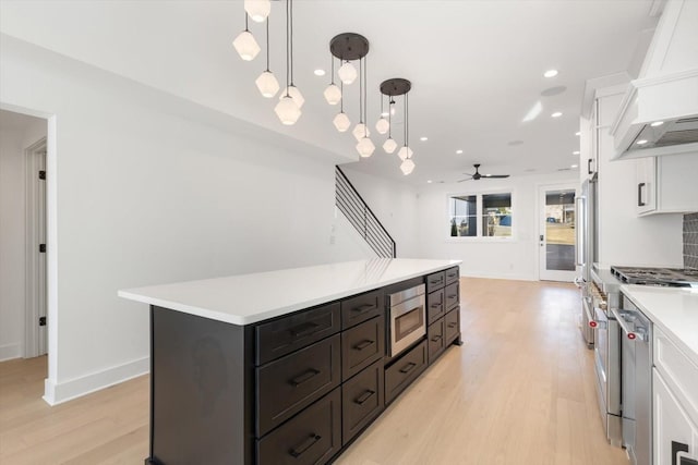 kitchen with white cabinets, a kitchen island, decorative light fixtures, decorative backsplash, and light hardwood / wood-style flooring