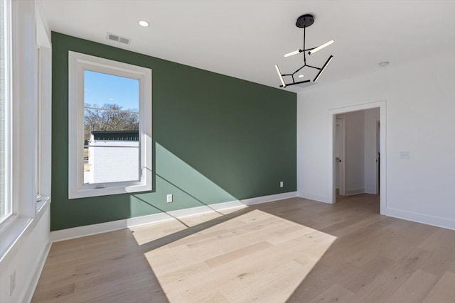 unfurnished room with light wood-type flooring and a chandelier