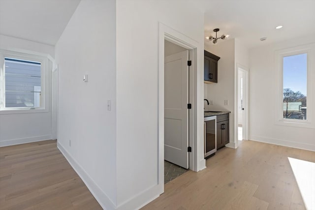 hallway with light wood-type flooring, wine cooler, plenty of natural light, and sink