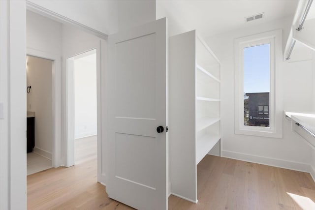 walk in closet with light hardwood / wood-style flooring