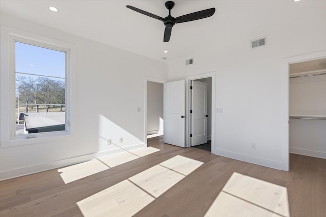 unfurnished bedroom with ceiling fan, hardwood / wood-style flooring, a closet, and a spacious closet