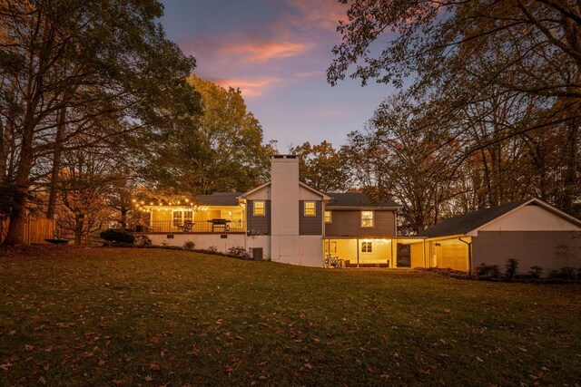 back house at dusk featuring a yard and central air condition unit