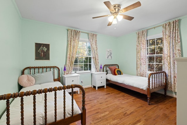 bedroom with crown molding, light wood-type flooring, and ceiling fan