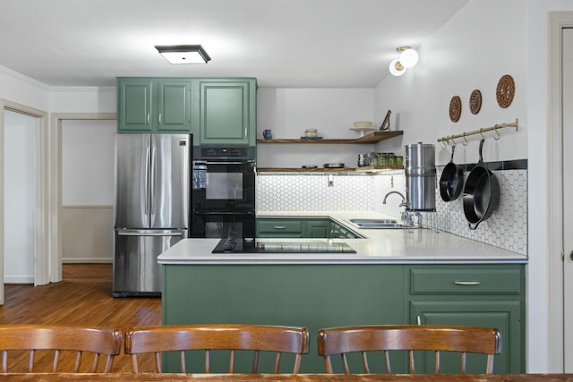 kitchen featuring black appliances, kitchen peninsula, green cabinetry, and sink