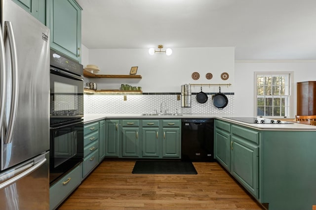 kitchen featuring sink, black appliances, decorative backsplash, and green cabinetry