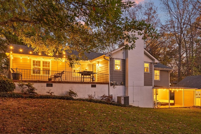 back house at dusk featuring central AC and a yard