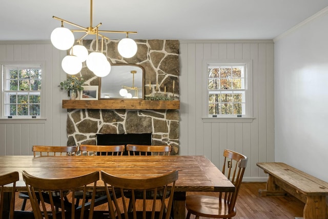 dining room with crown molding, hardwood / wood-style floors, wooden walls, and a fireplace