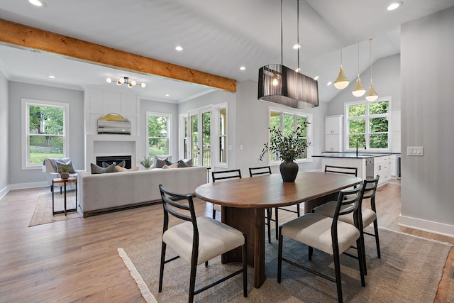 dining area featuring a large fireplace, sink, light hardwood / wood-style floors, and lofted ceiling