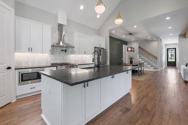 kitchen featuring sink, stainless steel appliances, a large island, and wall chimney exhaust hood