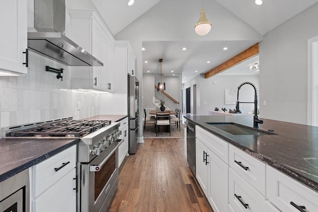 kitchen with white cabinets, appliances with stainless steel finishes, wall chimney exhaust hood, sink, and dark hardwood / wood-style floors