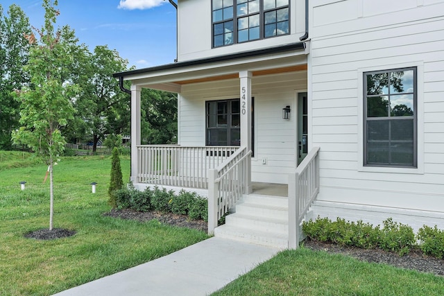 view of exterior entry featuring a yard and a porch