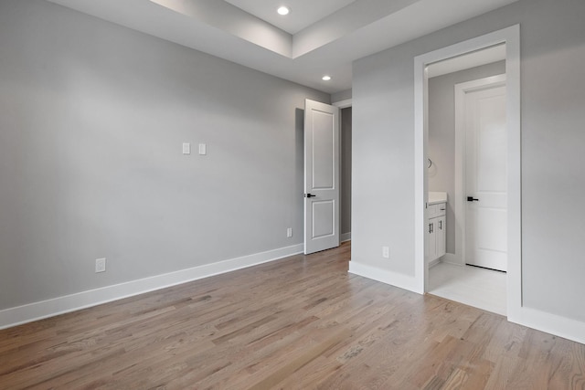 unfurnished bedroom featuring connected bathroom and light hardwood / wood-style floors