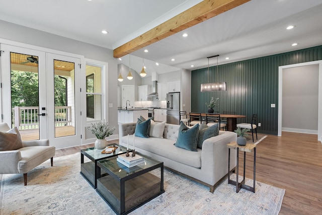 living room featuring sink, beamed ceiling, french doors, and light wood-type flooring