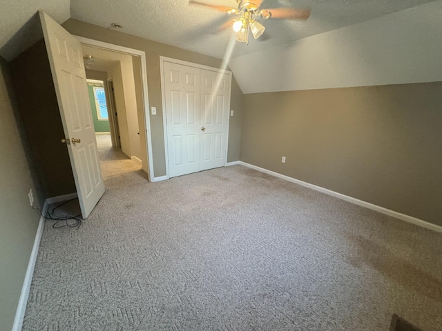 additional living space with vaulted ceiling, baseboards, carpet floors, and a textured ceiling