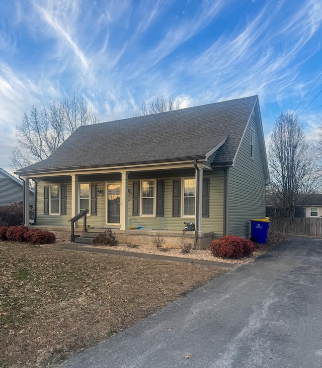 view of front of house featuring a porch, fence, and roof with shingles