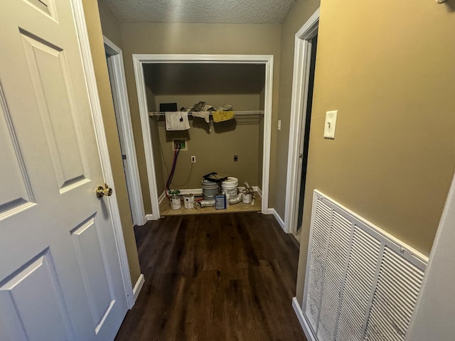 hallway featuring baseboards, wood finished floors, visible vents, and a textured ceiling