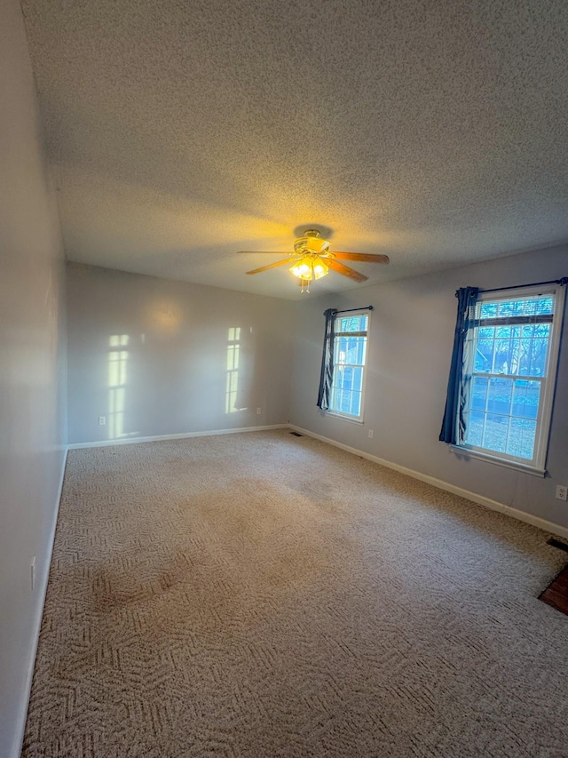 carpeted empty room featuring a ceiling fan, baseboards, and a textured ceiling