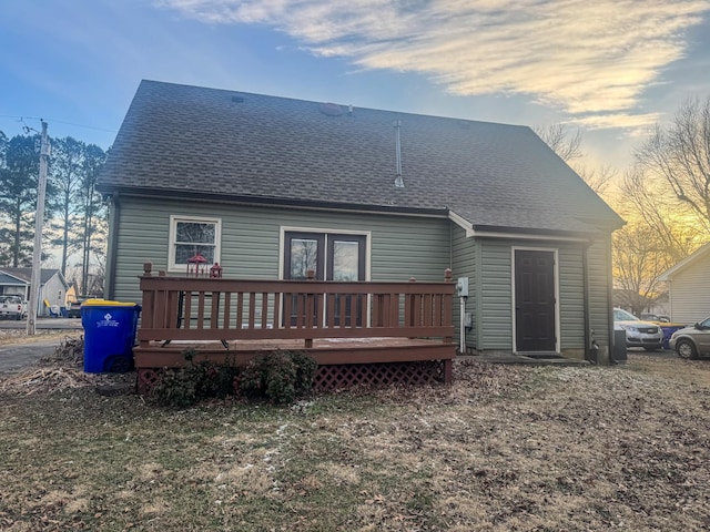 rear view of property with a deck and a shingled roof