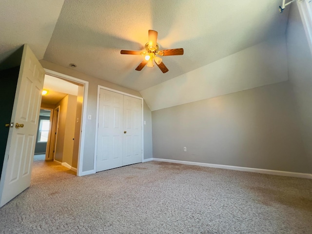 unfurnished bedroom with vaulted ceiling, baseboards, carpet floors, and a textured ceiling