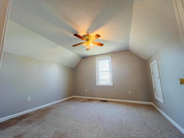 additional living space featuring visible vents, baseboards, carpet, lofted ceiling, and a textured ceiling