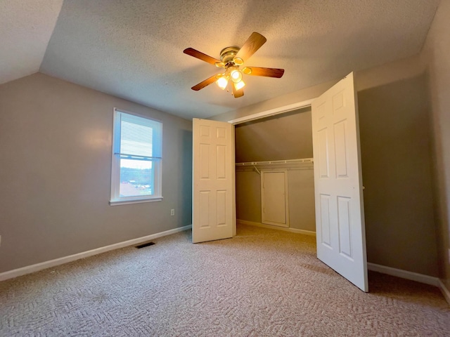 unfurnished bedroom with vaulted ceiling, visible vents, a textured ceiling, and carpet floors