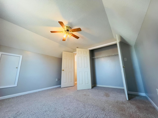 unfurnished bedroom with carpet, baseboards, vaulted ceiling, a closet, and a textured ceiling