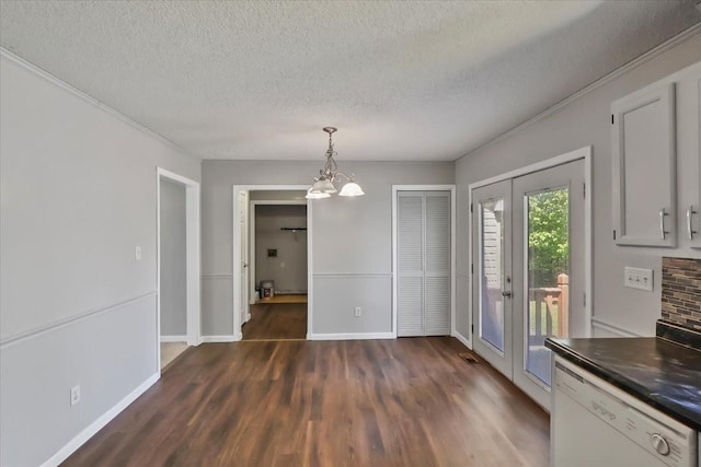 unfurnished dining area with french doors, a textured ceiling, baseboards, and dark wood-style floors