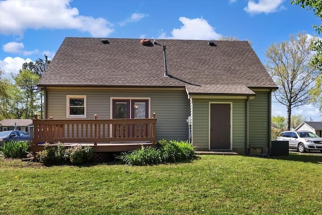 rear view of property with roof with shingles, a deck, and a lawn