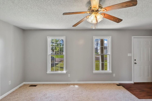 unfurnished room featuring carpet flooring, visible vents, a textured ceiling, and a ceiling fan