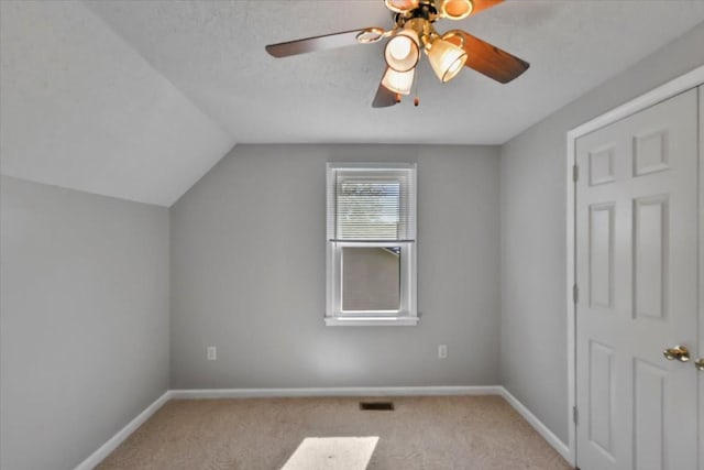 additional living space featuring visible vents, ceiling fan, carpet floors, and lofted ceiling