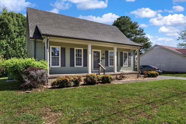 view of front of house with a shingled roof, covered porch, and a front yard